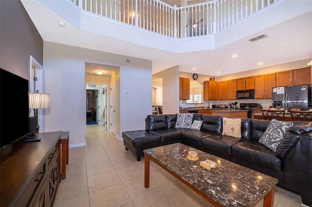 living room with sink, light tile floors, and a high ceiling