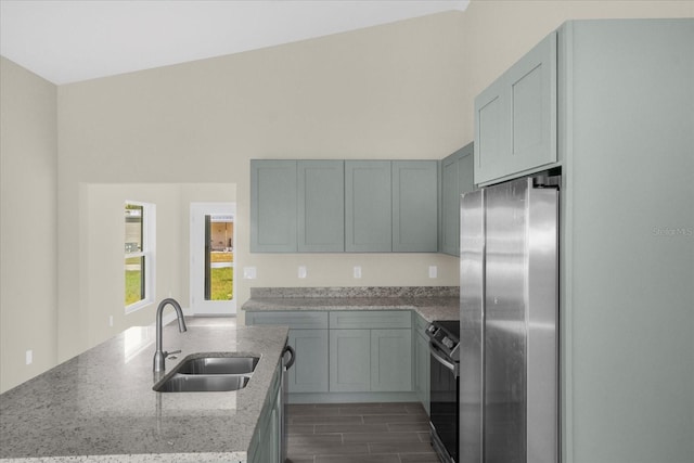 kitchen featuring high vaulted ceiling, sink, stainless steel appliances, and light stone countertops