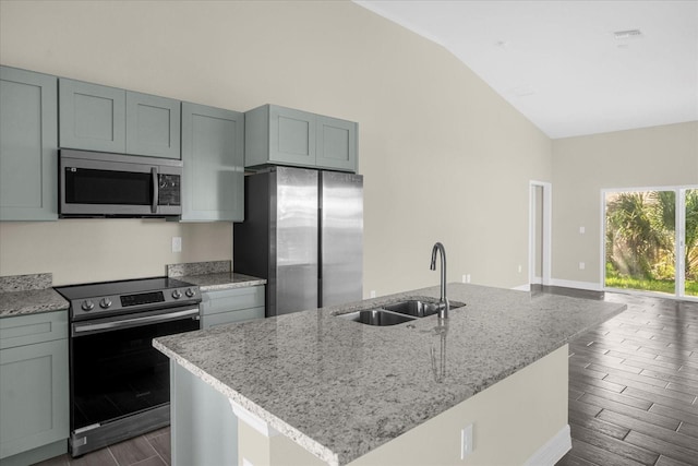 kitchen featuring sink, appliances with stainless steel finishes, a center island with sink, and vaulted ceiling