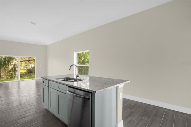 kitchen featuring light stone counters, sink, dishwasher, dark wood-type flooring, and a center island with sink