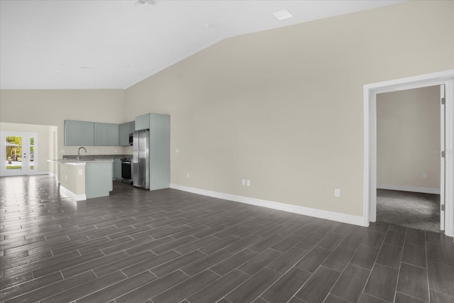 unfurnished living room with high vaulted ceiling, sink, and dark wood-type flooring