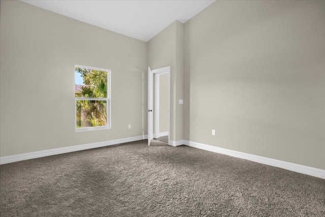 carpeted spare room with high vaulted ceiling