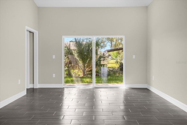 unfurnished room featuring a healthy amount of sunlight, dark hardwood / wood-style flooring, and a towering ceiling