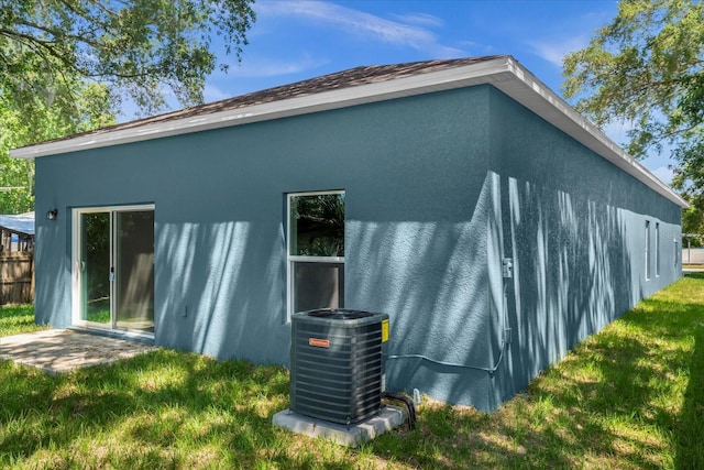 rear view of property featuring a lawn and central air condition unit