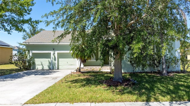 view of property hidden behind natural elements featuring a garage and a front lawn