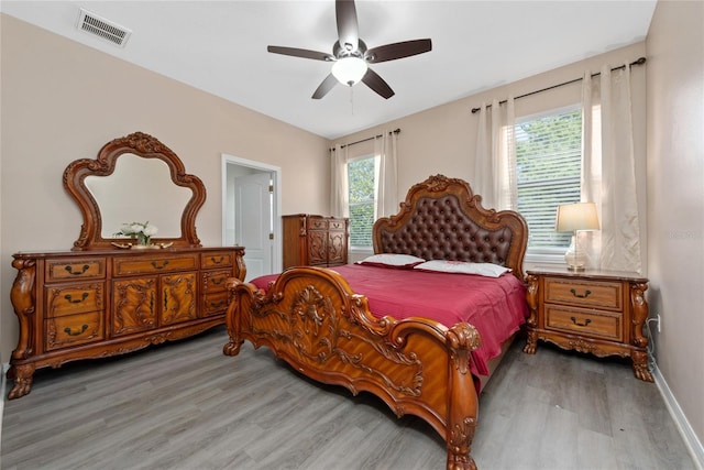 bedroom with ceiling fan, multiple windows, and light hardwood / wood-style flooring