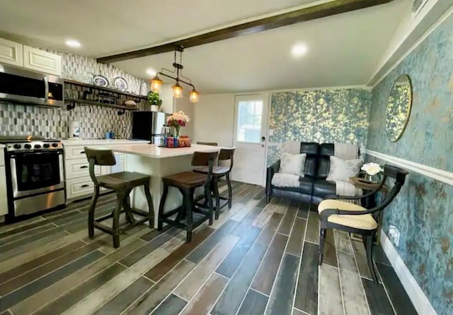 kitchen featuring lofted ceiling with beams, dark hardwood / wood-style flooring, appliances with stainless steel finishes, and white cabinetry