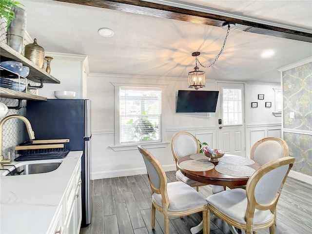 dining room featuring sink, light hardwood / wood-style floors, crown molding, and an inviting chandelier