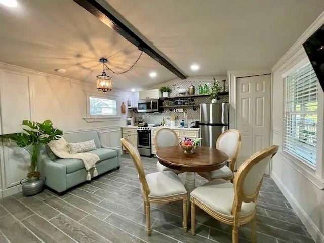 dining room featuring an inviting chandelier, lofted ceiling with beams, and hardwood / wood-style floors