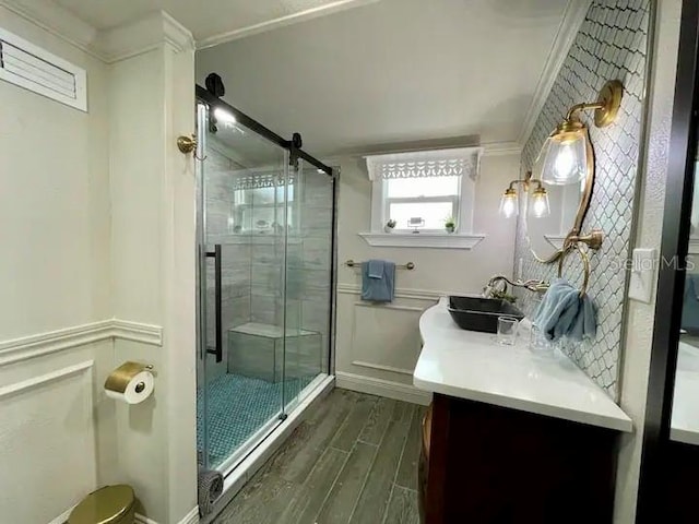 bathroom with wood-type flooring, a shower with door, vanity, and crown molding