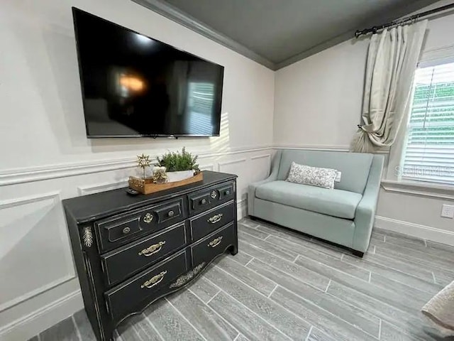 sitting room with ornamental molding and light wood-type flooring