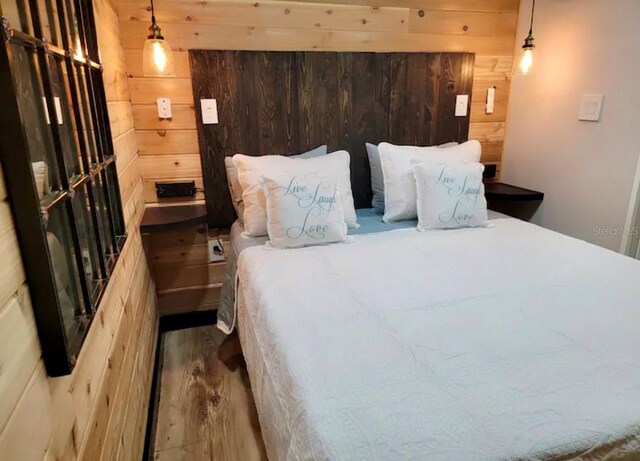 bedroom with wood-type flooring and wooden walls