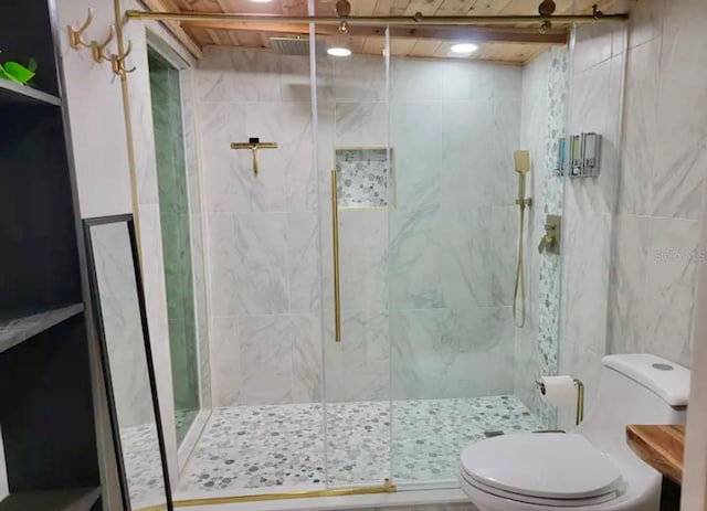 bathroom featuring a shower with door and toilet