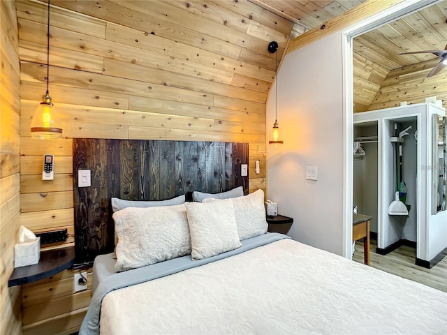 bedroom featuring a closet, wood ceiling, lofted ceiling, wooden walls, and light hardwood / wood-style flooring