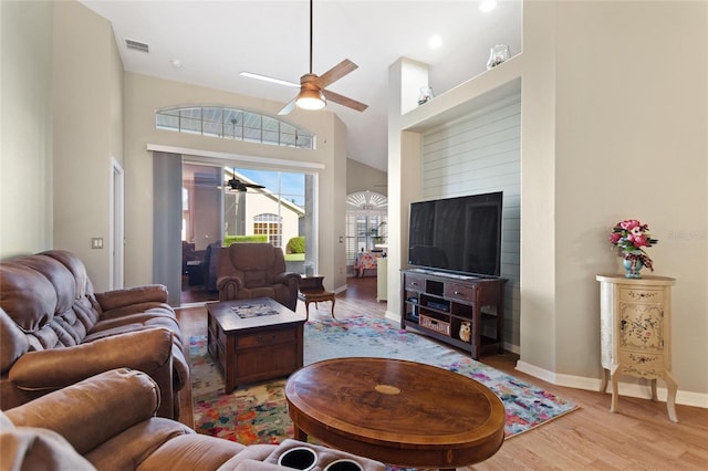 living room featuring high vaulted ceiling, ceiling fan, a fireplace, and light hardwood / wood-style flooring