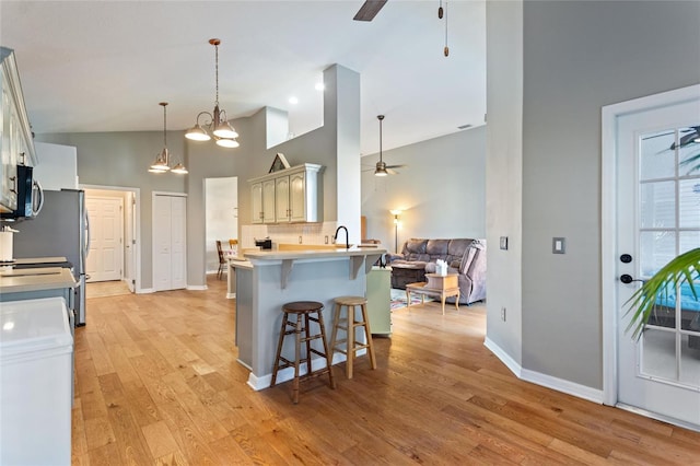 kitchen with light wood-type flooring, high vaulted ceiling, and ceiling fan with notable chandelier