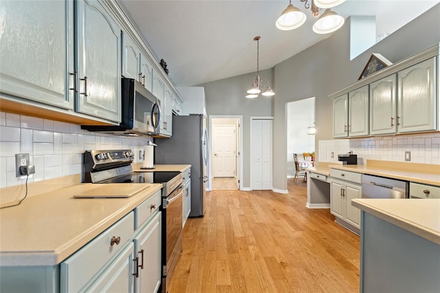 kitchen featuring hanging light fixtures, backsplash, stainless steel appliances, and light hardwood / wood-style flooring