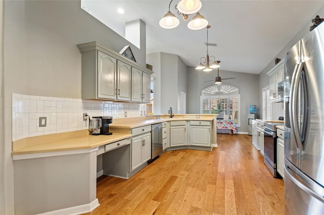 kitchen featuring kitchen peninsula, appliances with stainless steel finishes, pendant lighting, gray cabinets, and light wood-type flooring