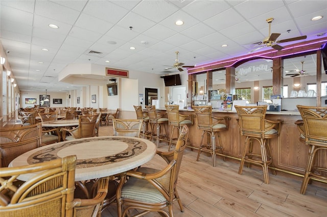 dining space with ceiling fan, light hardwood / wood-style flooring, and a drop ceiling