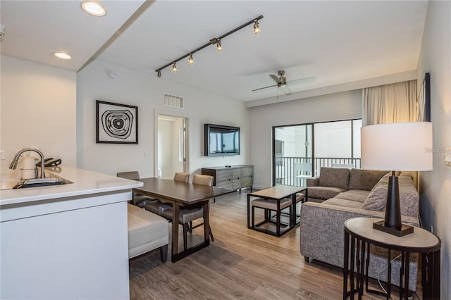 living room with ceiling fan, sink, track lighting, and hardwood / wood-style flooring