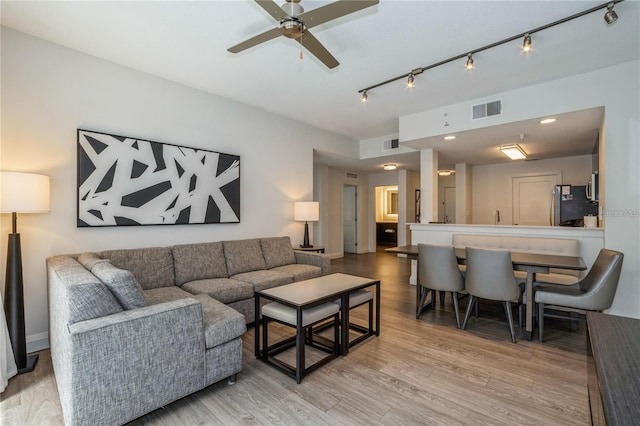 living room featuring light hardwood / wood-style flooring, ceiling fan, and track lighting