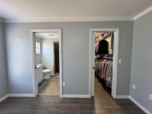 bedroom with a closet, a spacious closet, wood-type flooring, a textured ceiling, and connected bathroom