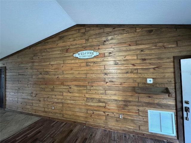 interior space with wood walls, dark hardwood / wood-style flooring, and vaulted ceiling