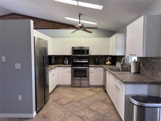 kitchen featuring stainless steel appliances, sink, ceiling fan, and vaulted ceiling with skylight