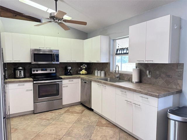 kitchen with ceiling fan, backsplash, sink, white cabinets, and appliances with stainless steel finishes