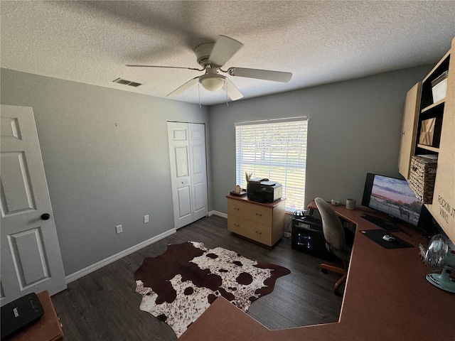 office area with a textured ceiling, dark wood-type flooring, and ceiling fan