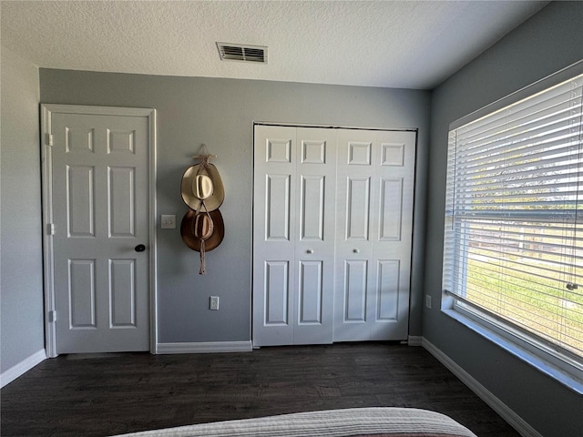 unfurnished bedroom featuring dark hardwood / wood-style flooring, a closet, and a textured ceiling