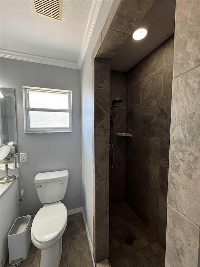 bathroom featuring tiled shower, crown molding, a textured ceiling, tile floors, and toilet