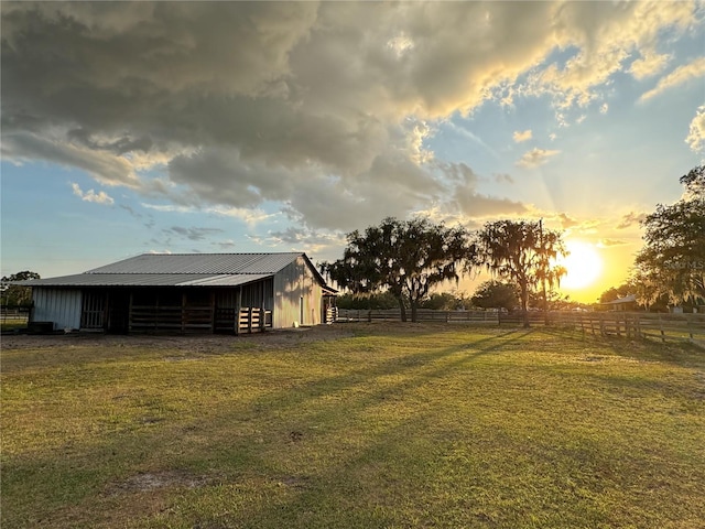 yard at dusk featuring a rural view and an outdoor structure