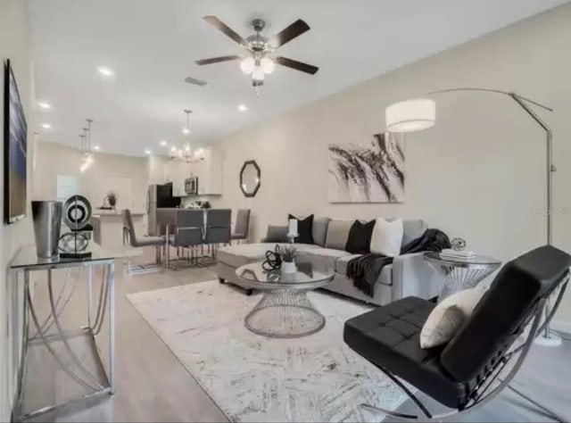 living room with ceiling fan with notable chandelier and recessed lighting