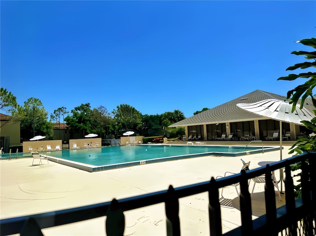 community pool with a patio and fence