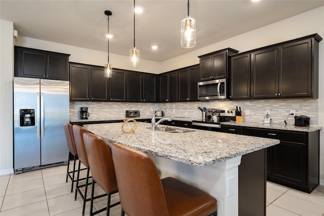 kitchen with decorative light fixtures, tasteful backsplash, stainless steel appliances, and a kitchen island with sink