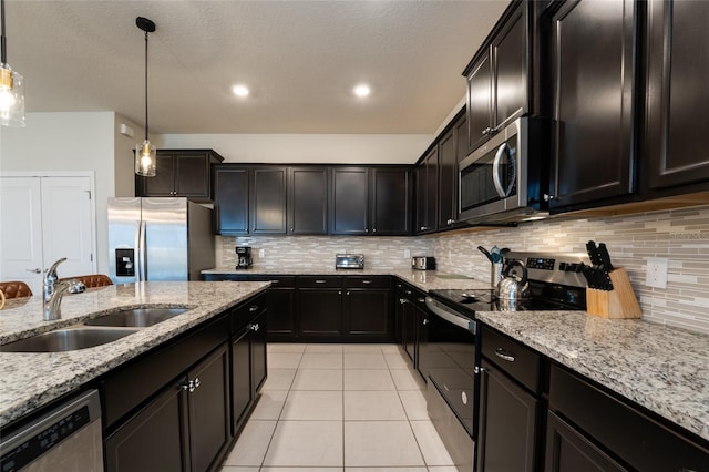 kitchen with tasteful backsplash, pendant lighting, stainless steel appliances, light stone countertops, and sink