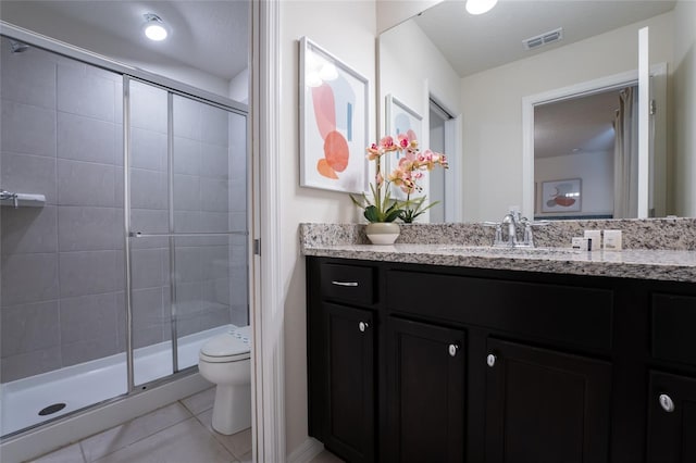 bathroom with tile flooring, a shower with door, toilet, and vanity with extensive cabinet space