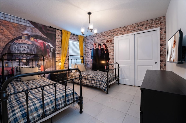 tiled bedroom featuring a notable chandelier, brick wall, and a closet