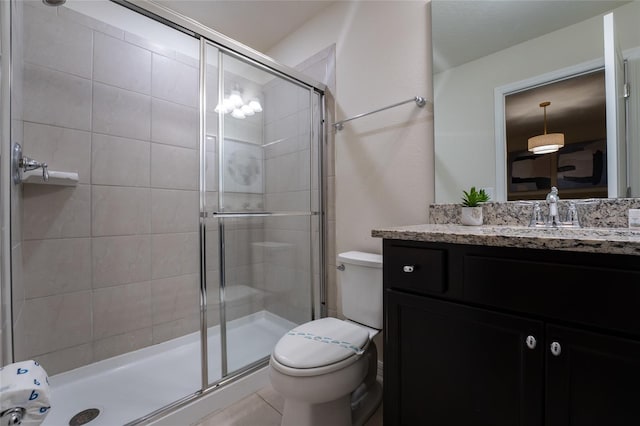 bathroom with tile flooring, toilet, large vanity, and a shower with door