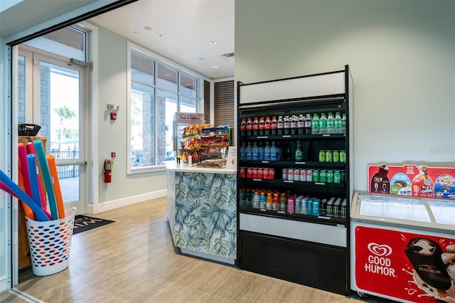 bar with wine cooler, light hardwood / wood-style flooring, and a wealth of natural light