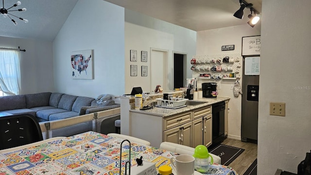 kitchen with light stone countertops, light hardwood / wood-style flooring, ceiling fan, vaulted ceiling, and black dishwasher