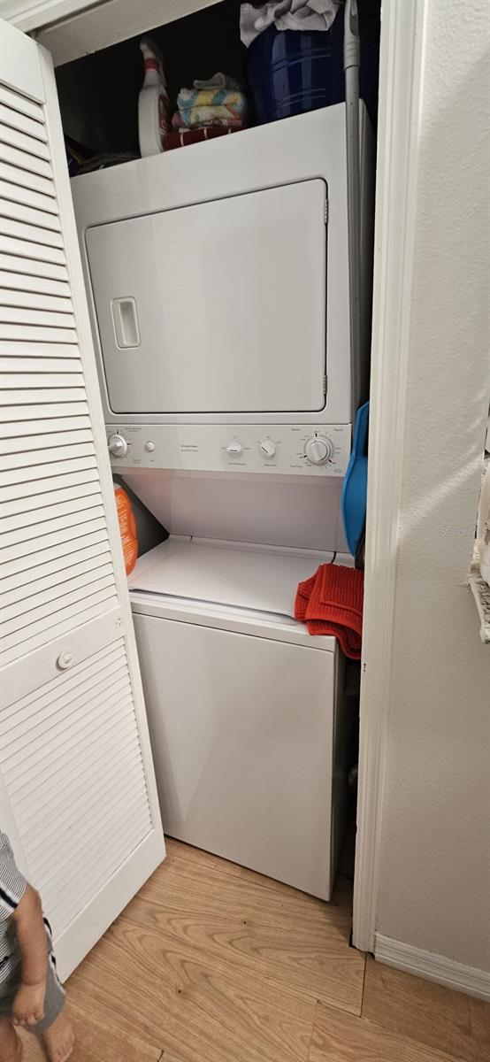 clothes washing area featuring light hardwood / wood-style floors and stacked washer and dryer