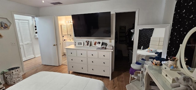 bedroom with a closet, light hardwood / wood-style floors, and connected bathroom