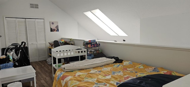 bedroom with a closet, dark hardwood / wood-style floors, and vaulted ceiling with skylight