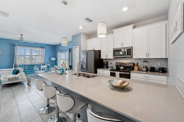 kitchen with appliances with stainless steel finishes, sink, a kitchen breakfast bar, pendant lighting, and tasteful backsplash