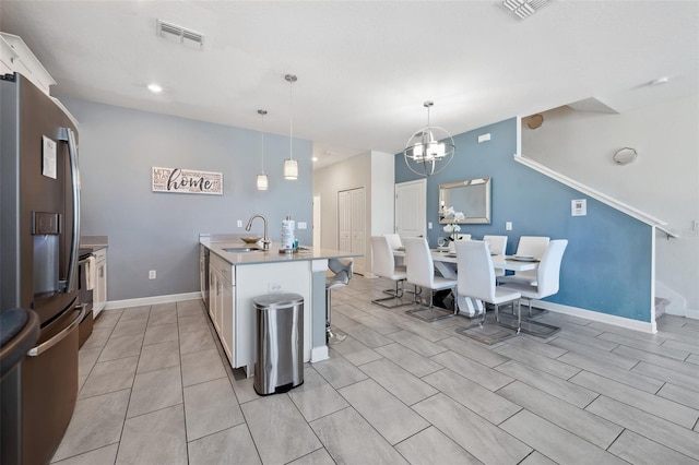 kitchen with decorative light fixtures, a breakfast bar, a notable chandelier, stainless steel fridge with ice dispenser, and sink