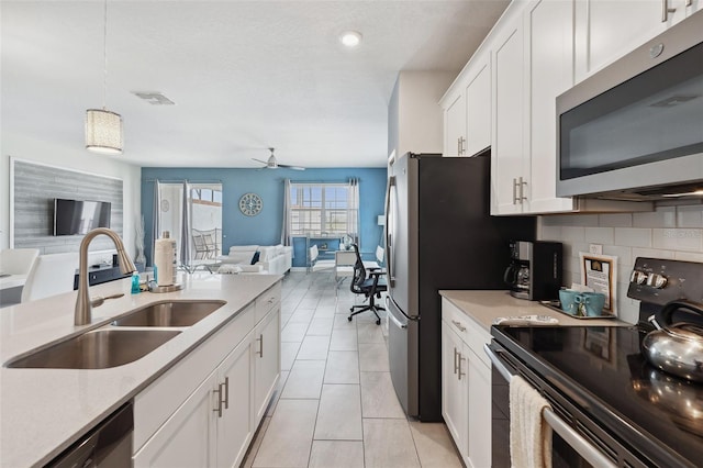 kitchen with appliances with stainless steel finishes, hanging light fixtures, ceiling fan, sink, and white cabinetry