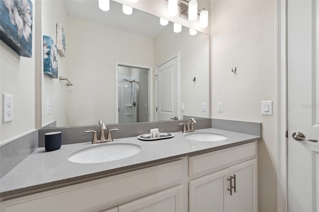 bathroom with a shower with shower door, dual sinks, and large vanity