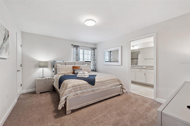 bedroom with connected bathroom and light carpet